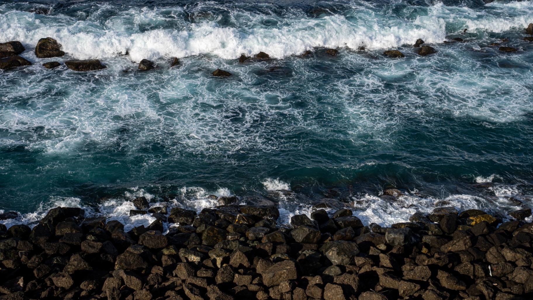 Waves crashing over dark coastal rocks