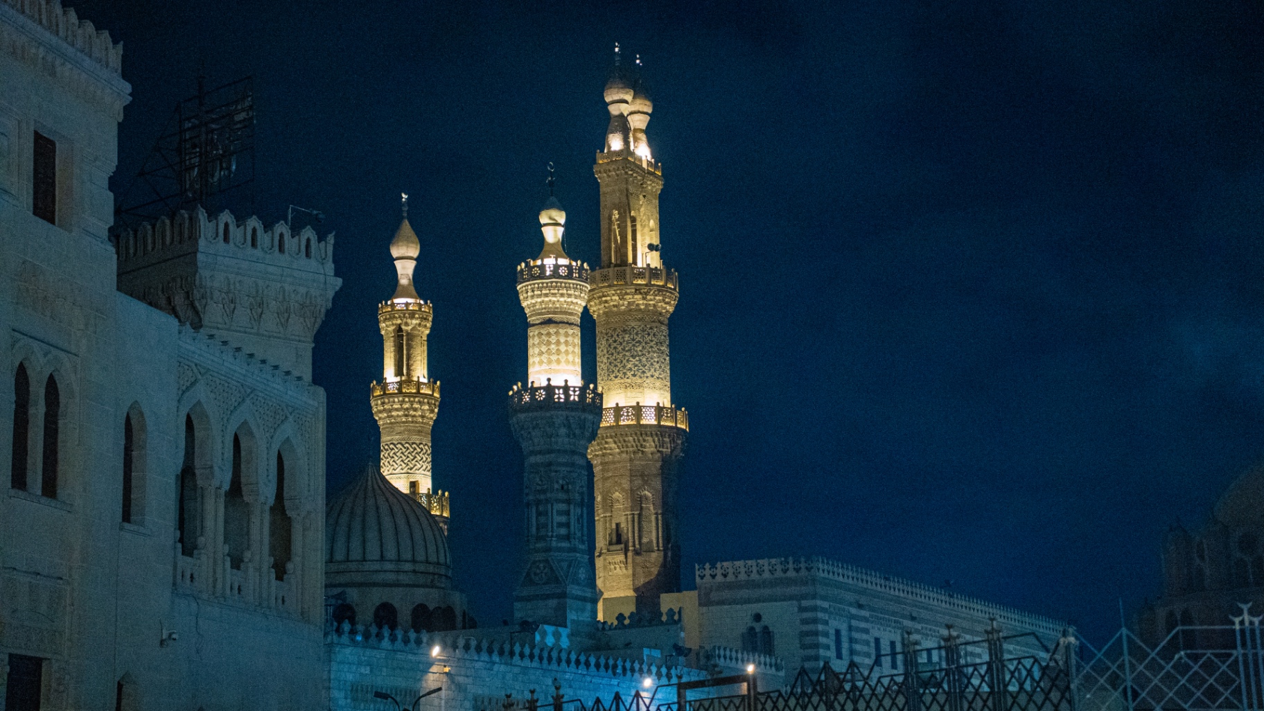 Illuminated mosque minarets against a deep blue night sky