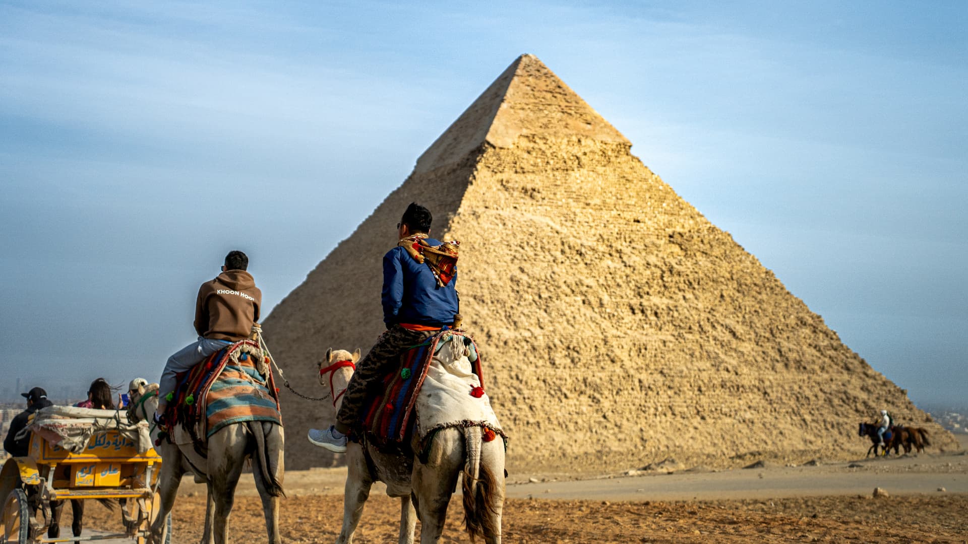 Camel riders approaching the Great Pyramid of Giza
