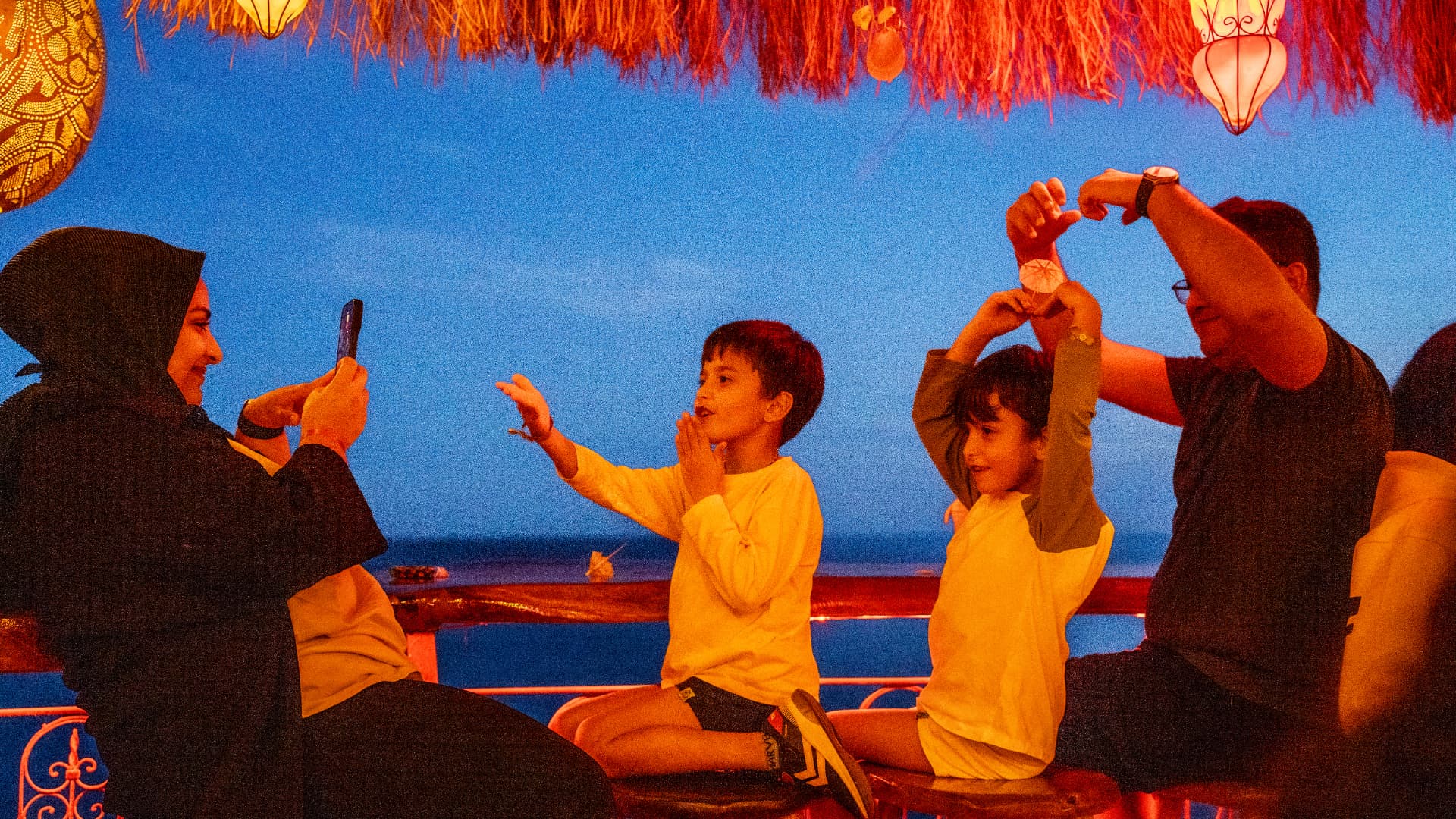 A family playing together under lanterns at sunset by the sea